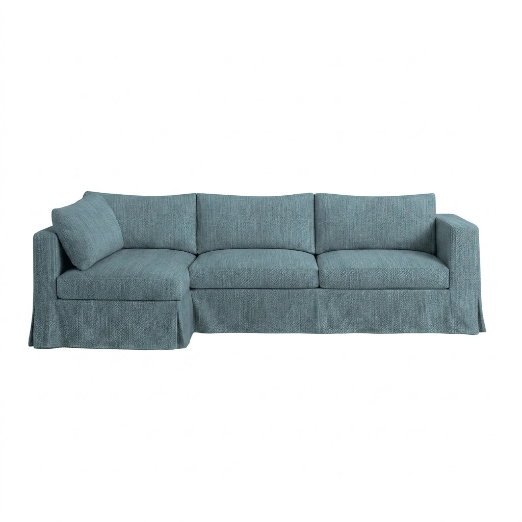 A three-seat slipcovered sofa in a textured slate blue fabric, featuring a single matching throw pillow, a skirted base, and wide armrests, shown against a plain white background.